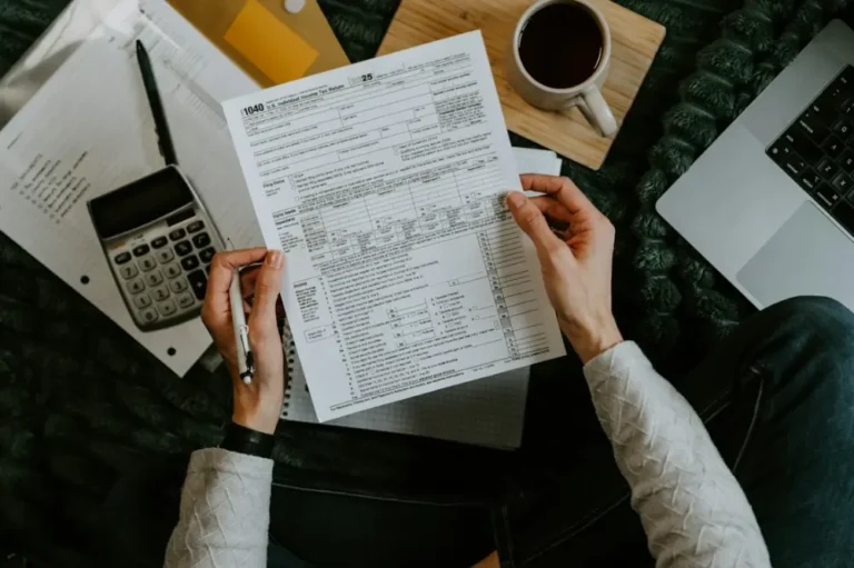 Manos sujetando un formulario junto a una calculadora