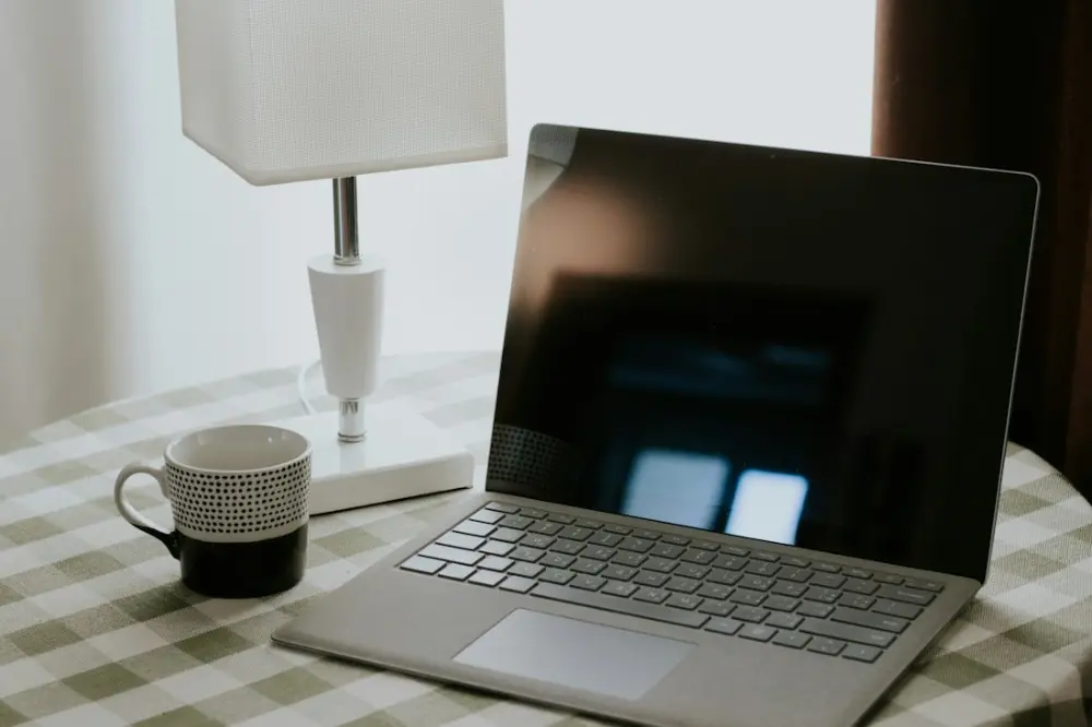 Portátil, taza y lámpara sobre un escritorio donde se gestionan clientes