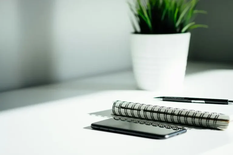Bolígrafo, cuaderno y teléfono sobre una mesa de trabajo
