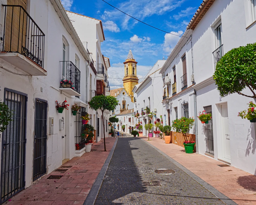 Calle de casas blancas con macetas en la Costa del Sol